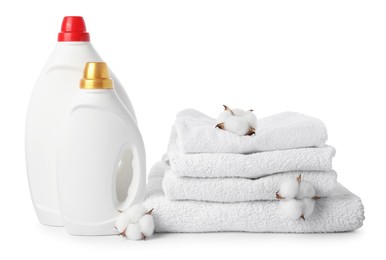 Photo of Bottles of fabric softener, stacked towels and cotton flowers isolated on white
