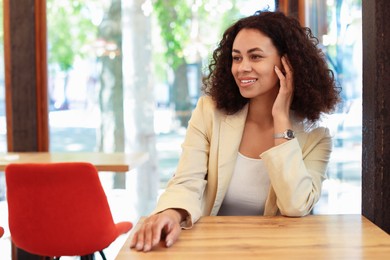 Photo of Portrait of smiling Latin American woman at table in cafe