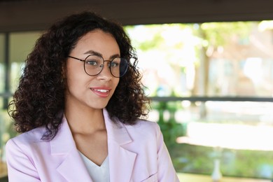 Photo of Portrait of smiling Latin American woman in cafe. Space for text