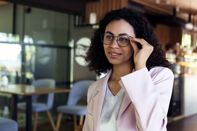 Photo of Portrait of smiling Latin American woman in cafe. Space for text
