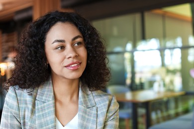 Photo of Portrait of smiling Latin American woman in cafe. Space for text