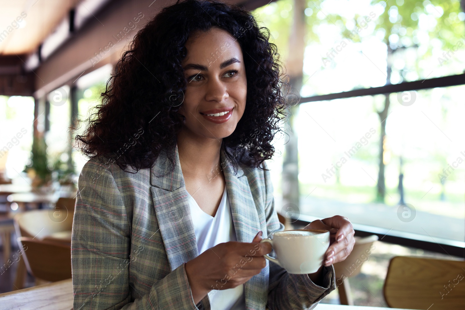 Portrait of smiling Latin American woman drinking coffee in cafe Photo of Portrait of smiling Latin American woman drinking coffee in cafe