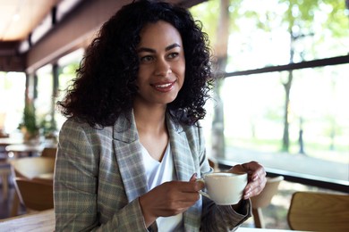 Photo of Portrait of smiling Latin American woman drinking coffee in cafe