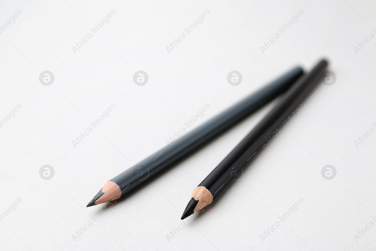 Two different eyebrow pencils on light background, closeup. Space for text Photo of Two different eyebrow pencils on light background, closeup. Space for text