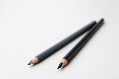 Photo of Two different eyebrow pencils on light background, closeup. Space for text