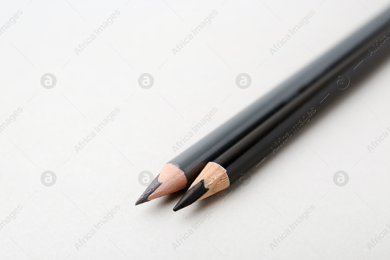 Two different eyebrow pencils on light background, closeup. Space for text Photo of Two different eyebrow pencils on light background, closeup. Space for text