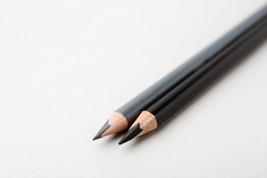 Photo of Two different eyebrow pencils on light background, closeup. Space for text