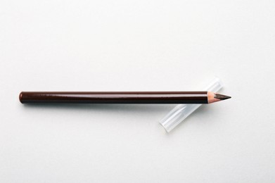 Photo of Brown eyebrow pencil on light background, top view