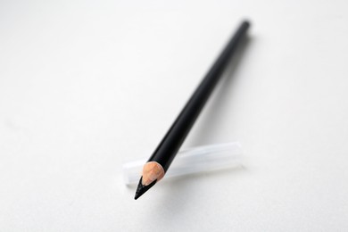 Photo of Black eyebrow pencil on light background, closeup. Space for text