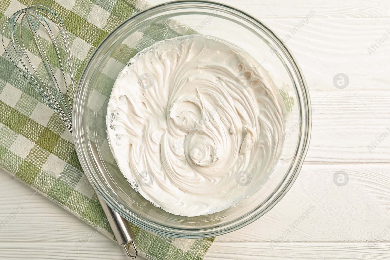 Bowl with whipped cream and whisk on white wooden table, top view Photo of Bowl with whipped cream and whisk on white wooden table, top view