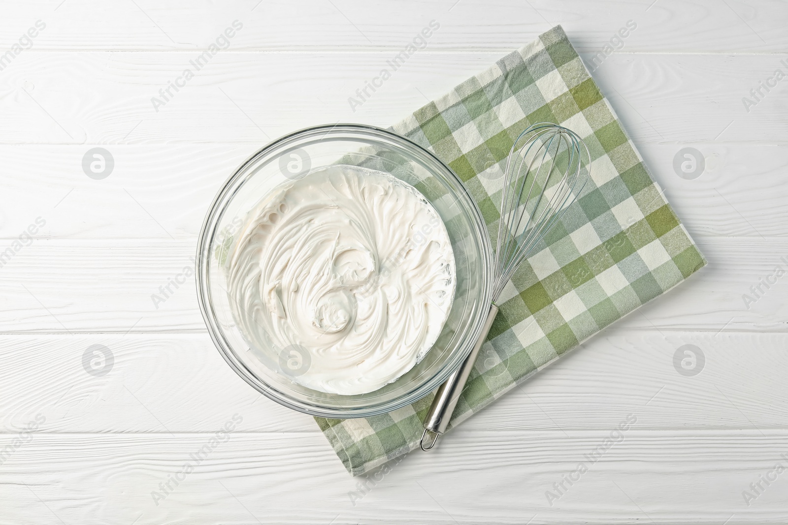 Bowl with whipped cream and whisk on white wooden table, top view Photo of Bowl with whipped cream and whisk on white wooden table, top view
