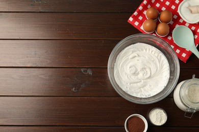 Photo of Bowl with whipped cream and ingredients on wooden table, flat lay. Space for text