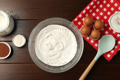 Photo of Bowl with whipped cream and ingredients on wooden table, flat lay