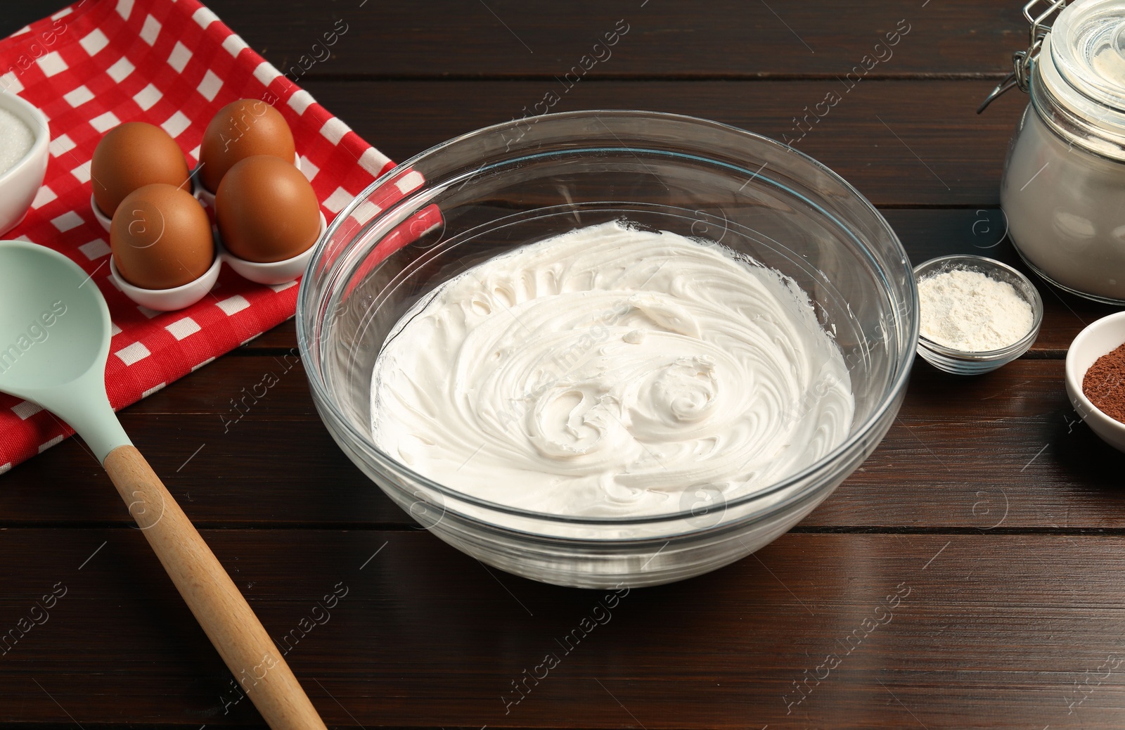 Bowl with whipped cream and ingredients on wooden table, closeup Photo of Bowl with whipped cream and ingredients on wooden table, closeup