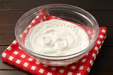 Photo of Bowl with whipped cream on wooden table, closeup