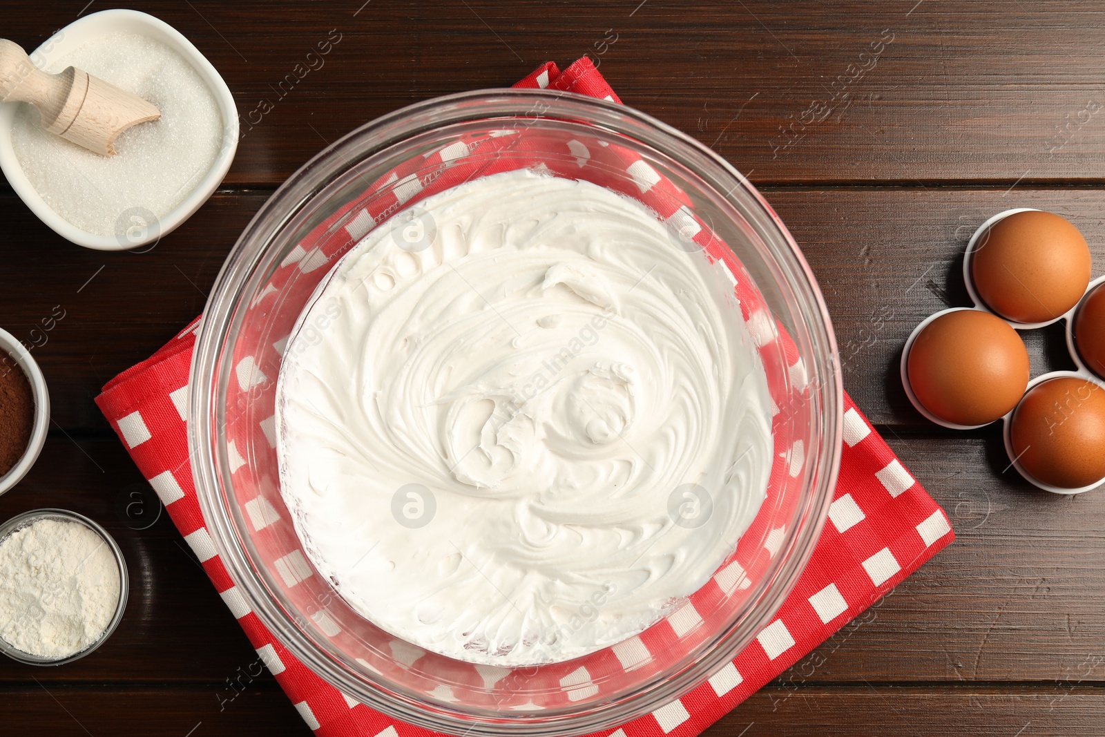 Bowl with whipped cream and ingredients on wooden table, flat lay Photo of Bowl with whipped cream and ingredients on wooden table, flat lay