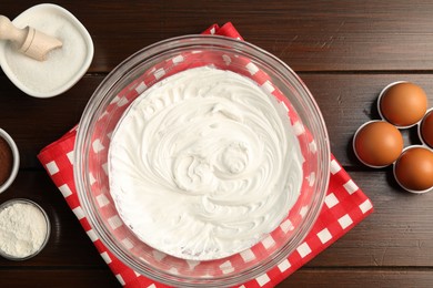 Photo of Bowl with whipped cream and ingredients on wooden table, flat lay