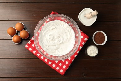 Photo of Bowl with whipped cream and ingredients on wooden table, flat lay