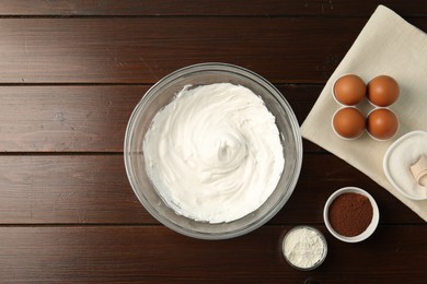 Photo of Bowl with whipped cream and ingredients on wooden table, flat lay. Space for text