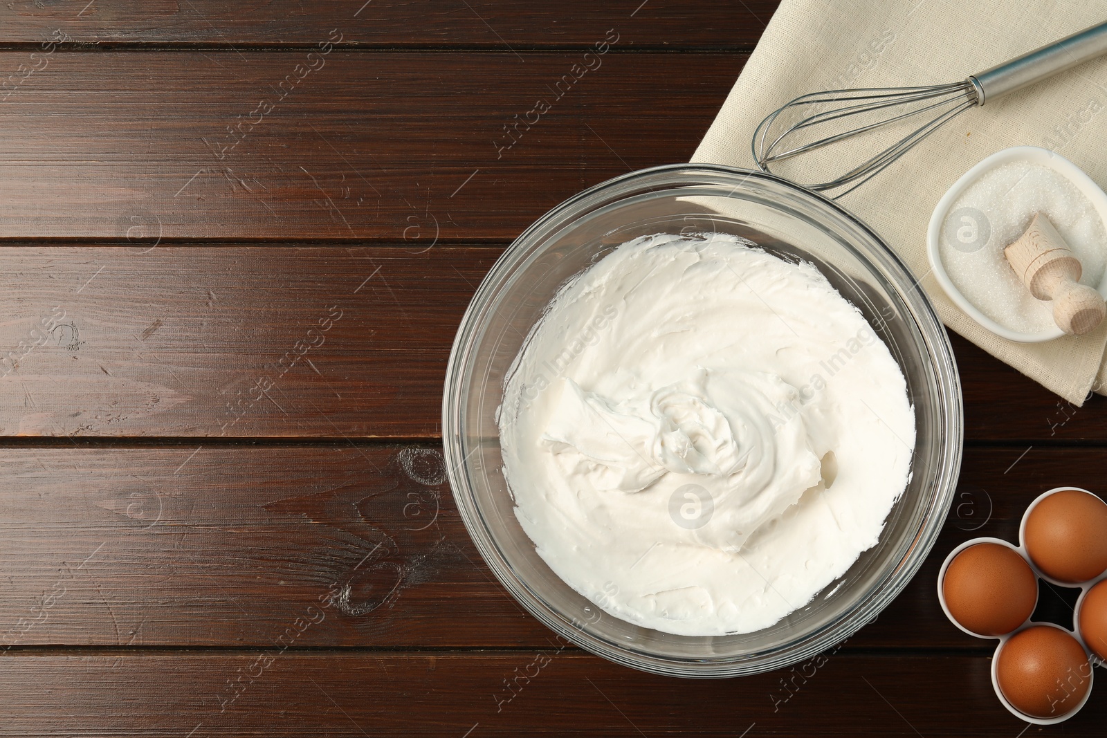 Bowl with whipped cream, whisk and ingredients on wooden table, flat lay. Space for text Photo of Bowl with whipped cream, whisk and ingredients on wooden table, flat lay. Space for text