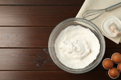 Photo of Bowl with whipped cream, whisk and ingredients on wooden table, flat lay. Space for text