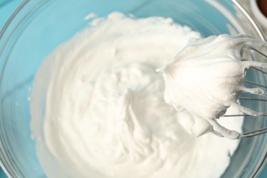 Photo of Bowl with whipped cream and whisk on light blue wooden table, top view