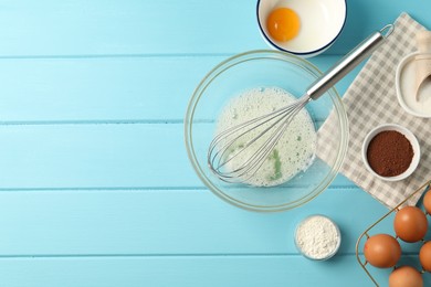 Photo of Making whipped cream. Bowl, whisk and ingredients on light blue wooden table, flat lay. Space for text