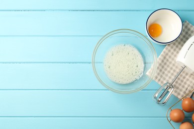 Photo of Making whipped cream. Bowl, hand mixer and ingredients on light blue wooden table, flat lay. Space for text