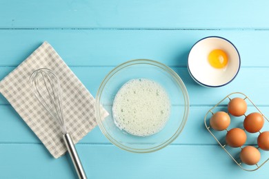 Photo of Making whipped cream. Bowl, whisk and ingredients on light blue wooden table, flat lay