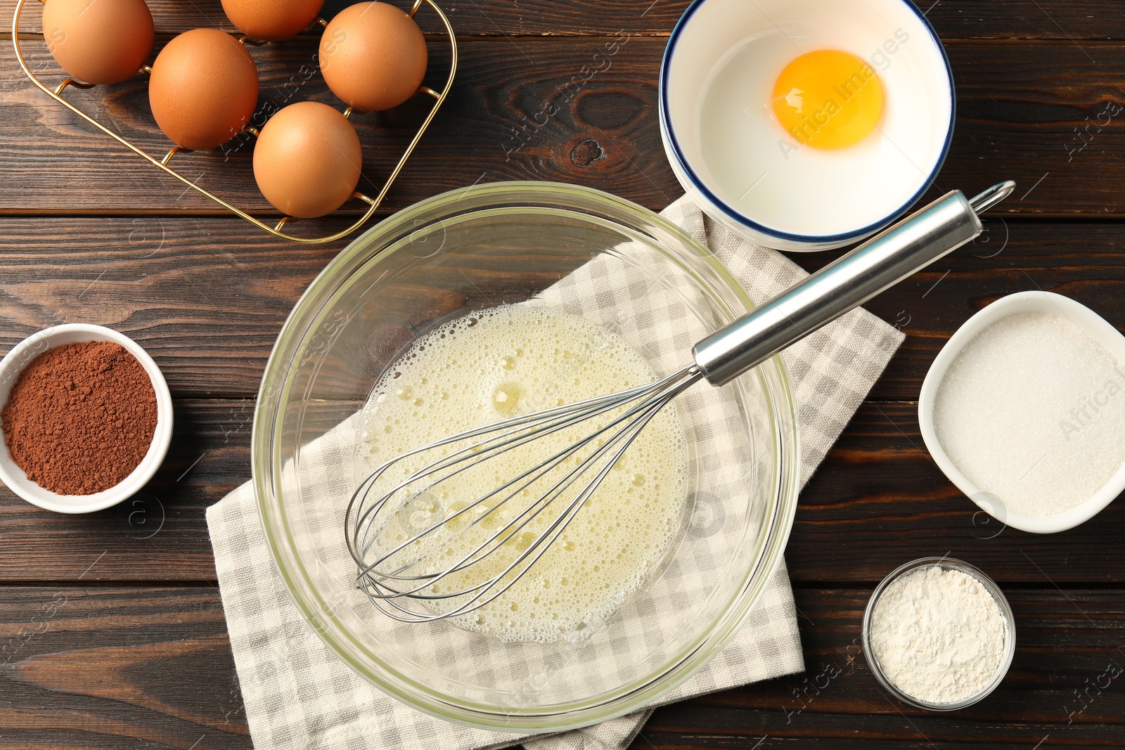 Making whipped cream. Bowl, whisk and ingredients on wooden table, flat lay Photo of Making whipped cream. Bowl, whisk and ingredients on wooden table, flat lay