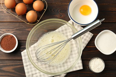 Photo of Making whipped cream. Bowl, whisk and ingredients on wooden table, flat lay