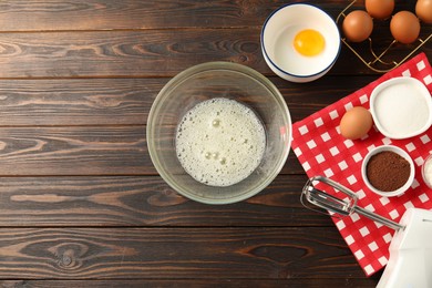 Photo of Making whipped cream. Bowl, whisk and ingredients on wooden table, flat lay. Space for text