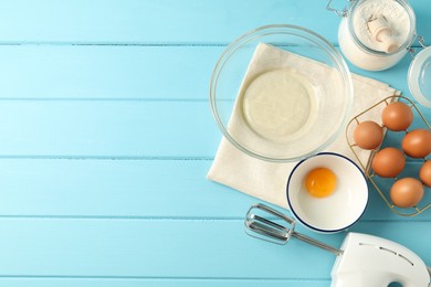 Photo of Making whipped cream. Bowl, hand mixer and ingredients on light blue wooden table, flat lay. Space for text