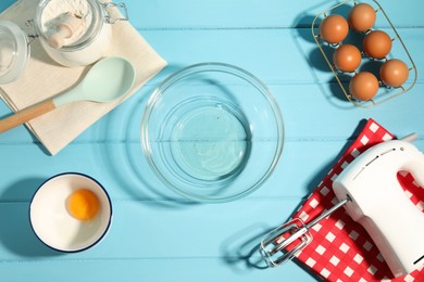 Photo of Making whipped cream. Bowl, hand mixer and ingredients on light blue wooden table, flat lay
