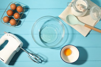 Photo of Making whipped cream. Bowl, hand mixer and ingredients on light blue wooden table, flat lay