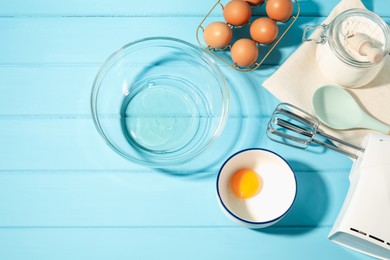 Photo of Making whipped cream. Bowl, hand mixer and ingredients on light blue wooden table, flat lay
