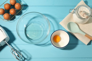 Photo of Making whipped cream. Bowl, hand mixer and ingredients on light blue wooden table, flat lay