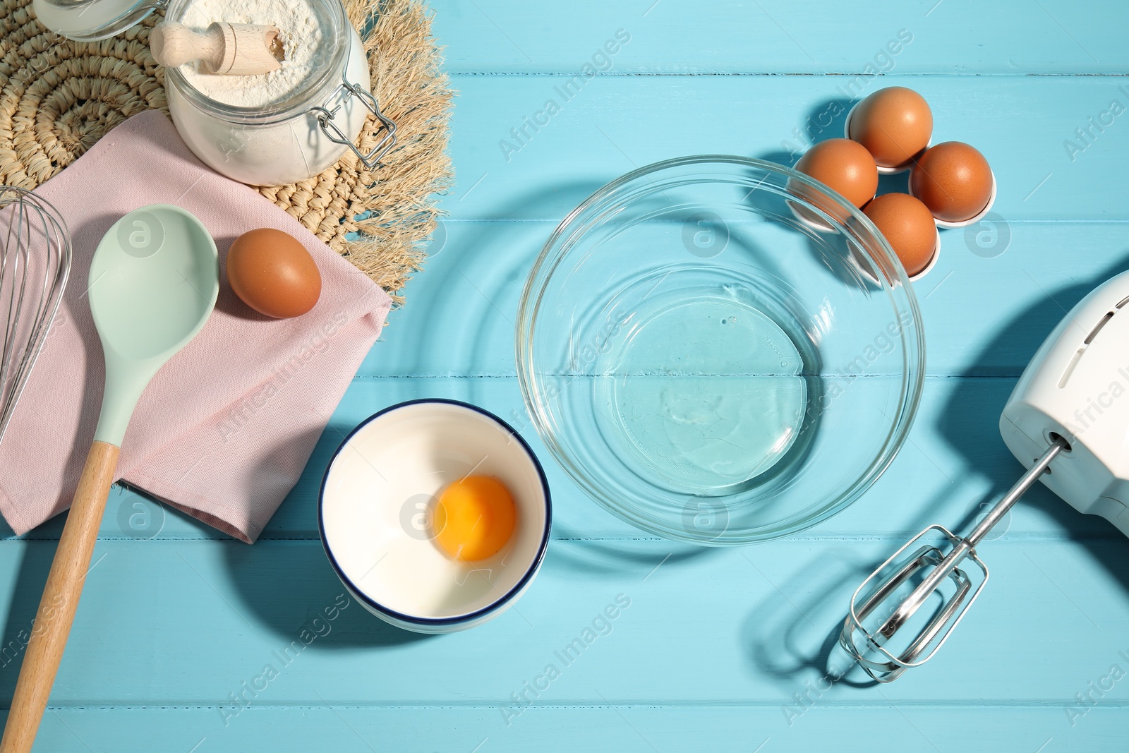Making whipped cream. Bowl, hand mixer and ingredients on light blue wooden table, flat lay Photo of Making whipped cream. Bowl, hand mixer and ingredients on light blue wooden table, flat lay