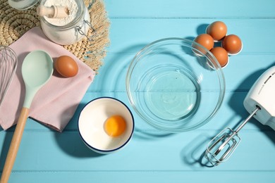 Photo of Making whipped cream. Bowl, hand mixer and ingredients on light blue wooden table, flat lay