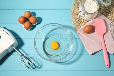 Photo of Making whipped cream. Bowl, hand mixer and ingredients on light blue wooden table, flat lay