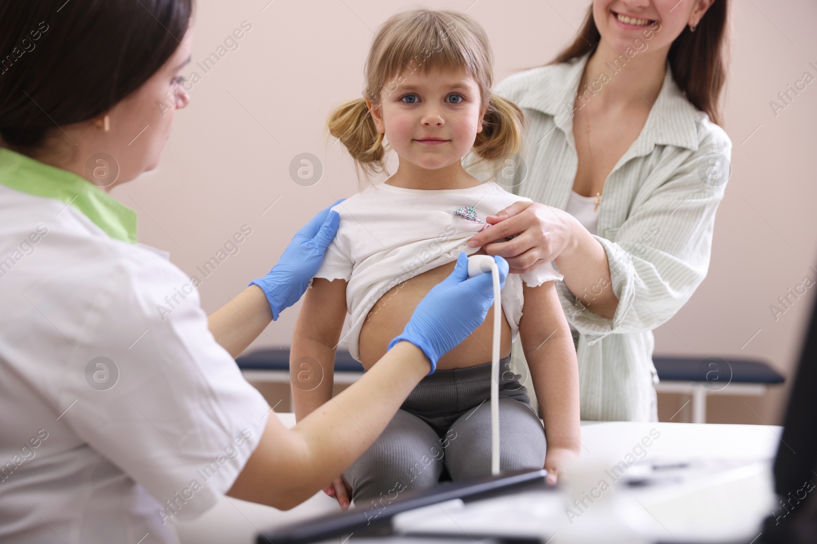 Sonographer conducting ultrasound examination of girl's heart. Mother and daughter having appointment with doctor in clinic Photo of Sonographer conducting ultrasound examination of girl's heart. Mother and daughter having appointment with doctor in clinic