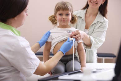Photo of Sonographer conducting ultrasound examination of girl's heart. Mother and daughter having appointment with doctor in clinic