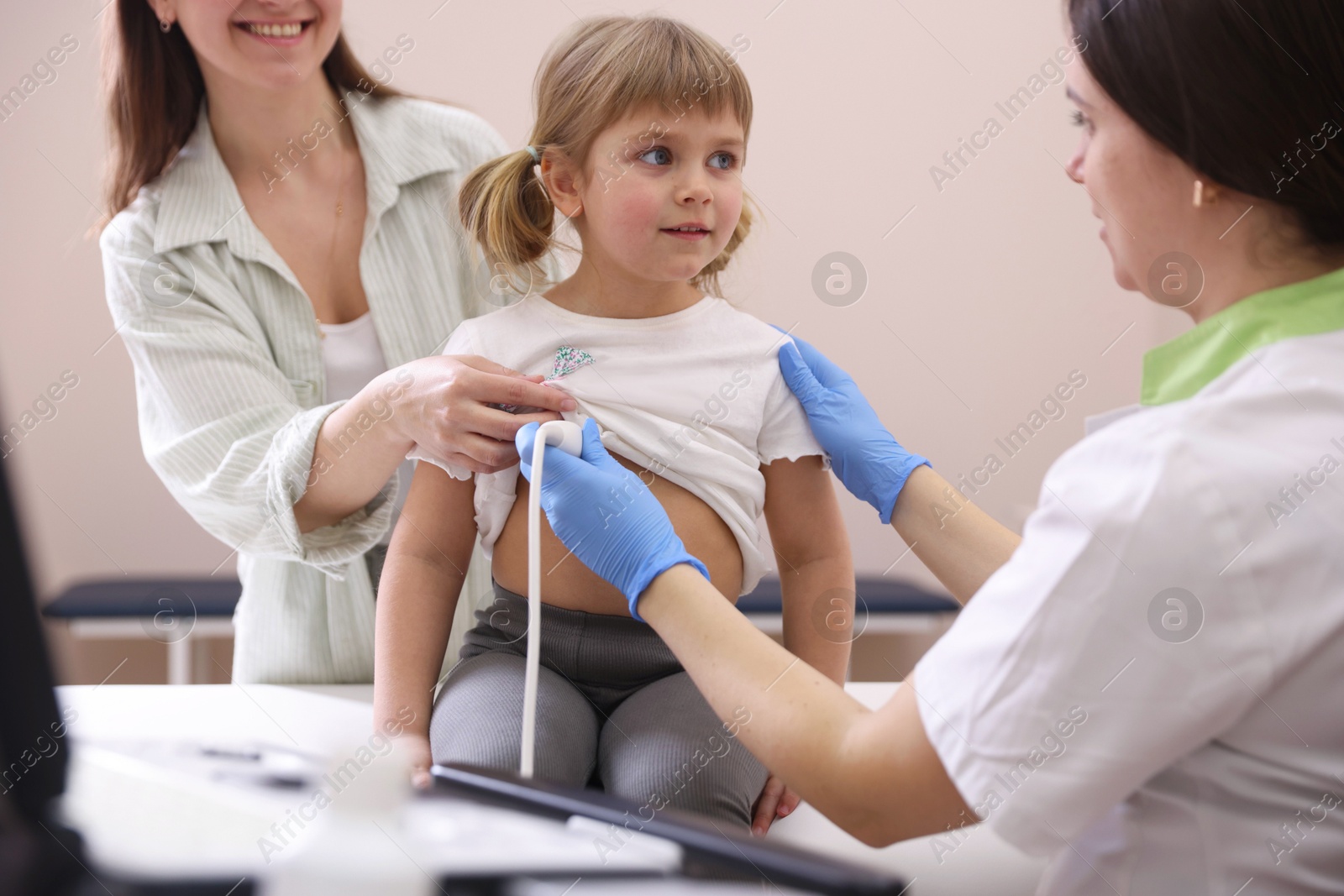Sonographer conducting ultrasound examination of girl's heart. Mother and daughter having appointment with doctor in clinic Photo of Sonographer conducting ultrasound examination of girl's heart. Mother and daughter having appointment with doctor in clinic