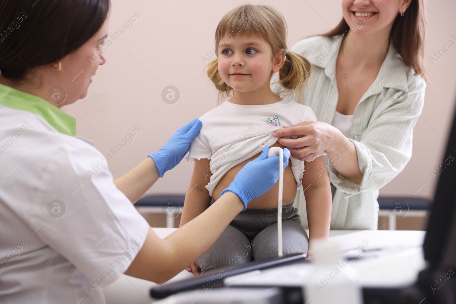 Sonographer conducting ultrasound examination of girl's heart. Mother and daughter having appointment with doctor in clinic Photo of Sonographer conducting ultrasound examination of girl's heart. Mother and daughter having appointment with doctor in clinic