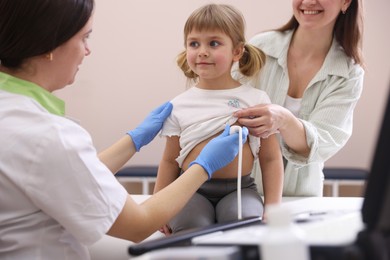 Photo of Sonographer conducting ultrasound examination of girl's heart. Mother and daughter having appointment with doctor in clinic