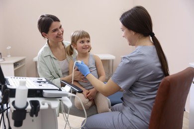 Photo of Sonographer conducting ultrasound examination of girl's heart. Mother and daughter having appointment with doctor in clinic
