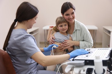 Photo of Sonographer conducting little girl's abdominal ultrasound examination. Mother and daughter having appointment with doctor in clinic