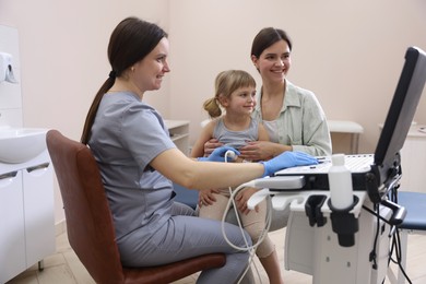 Photo of Sonographer conducting little girl's abdominal ultrasound examination. Mother and daughter having appointment with doctor in clinic