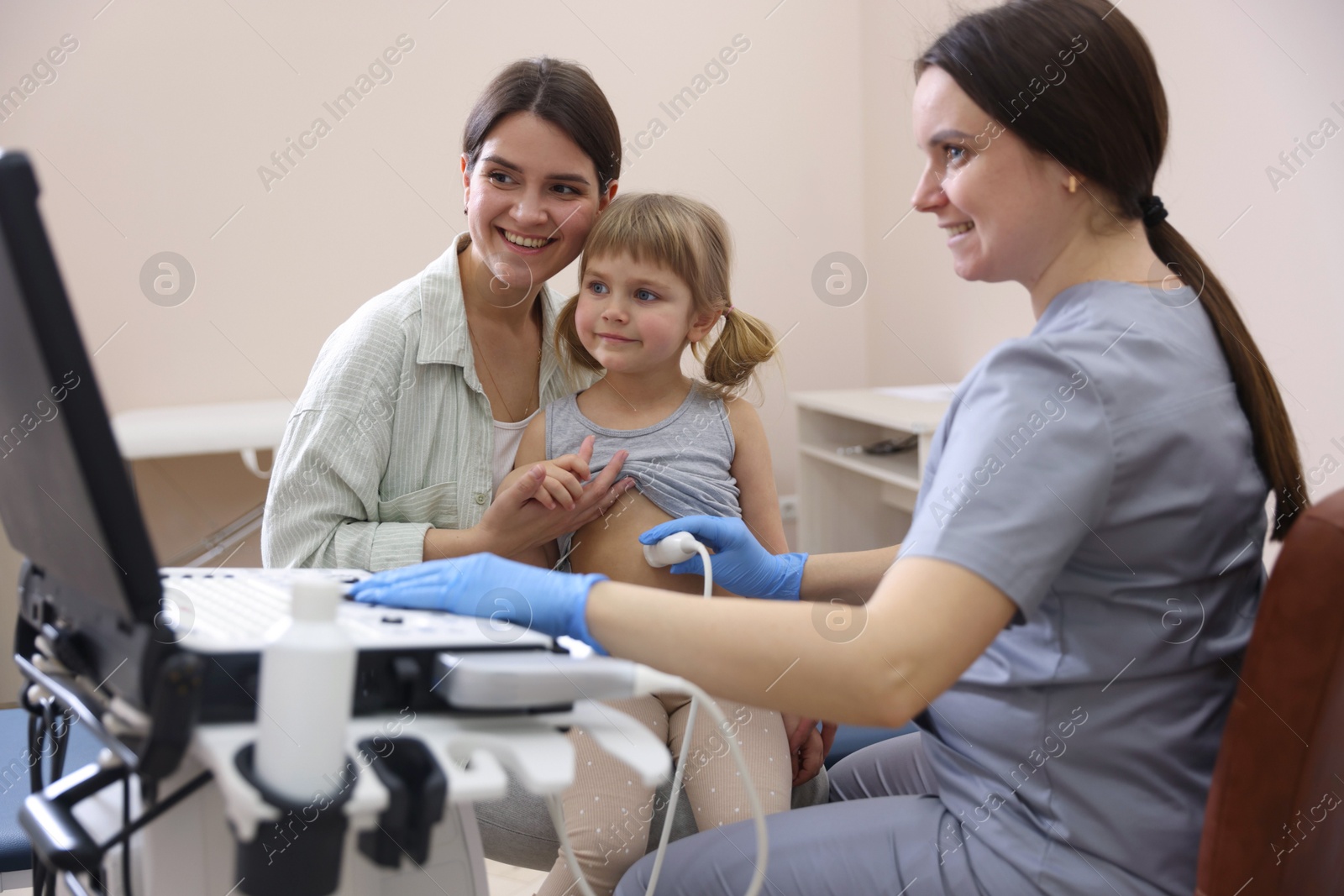Sonographer conducting little girl's abdominal ultrasound examination. Mother and daughter having appointment with doctor in clinic Photo of Sonographer conducting little girl's abdominal ultrasound examination. Mother and daughter having appointment with doctor in clinic