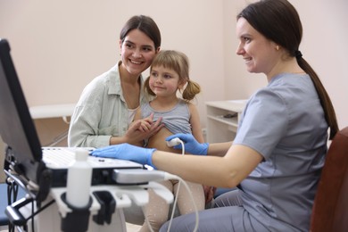 Photo of Sonographer conducting little girl's abdominal ultrasound examination. Mother and daughter having appointment with doctor in clinic